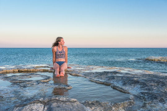 Young woman relaxing on the seashore enjoying the warm breeze