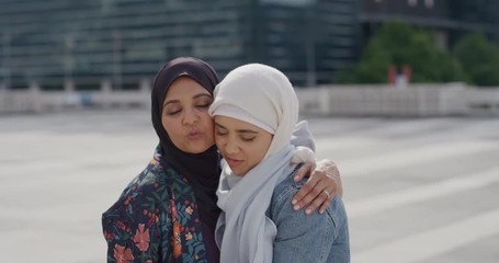 portrait beautiful muslim mother hugging sad daughter embracing in city wearing hijab headscarf slow motion