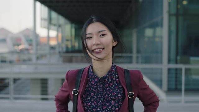 portrait of optimistic asian woman intern posing happy in city