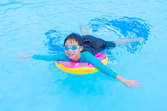 Young asian boy swimming with ring in pool