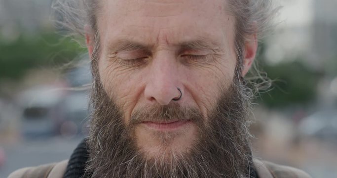 close up portrait mature bearded hippie man looking up pensive homeless guy living independent urban lifestyle in city wearing nose ring wrinkles aging