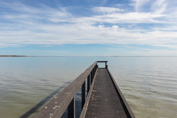 Fototapeta premium Small jetty with calm waters and blue skies