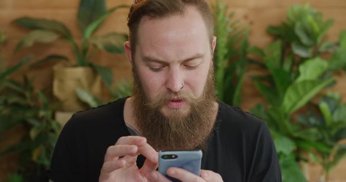 young caucasian man using smartphone portrait of bearded hipster browsing online looking pensive texting on mobile phone