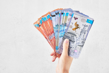 Tenge. The female hand holds many Kazakh bills on a white background close-up..