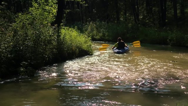 Annonymous family, father and son kayaking on the forest river, summer evening, handheld shot in 4K UHD