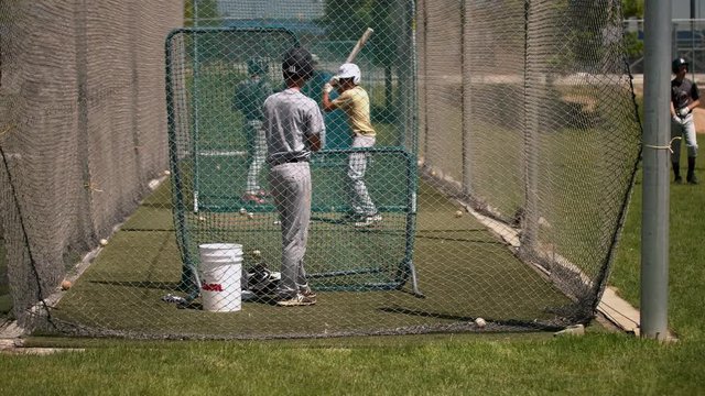 A group of young men are practicing baseball on a sunny day.