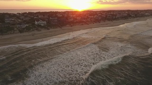 This is a video of a drone revealing the beach and waves of the Outer Banks of Corolla during sunset.
