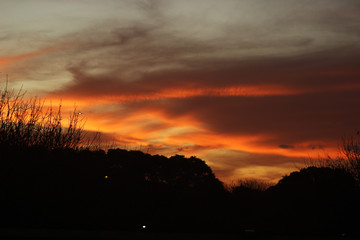 Fototapeta premium Cielo de atardecer con nubes anaranjadas hermosas sobre el campo