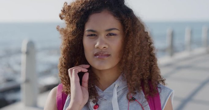 portrait pensive young hispanic woman running hand through hair contemplative beautiful female frizzy hairstyle on seaside background slow motion