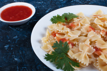 Cooked pasta with tomato sauce and greens.