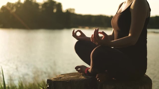 Mid shot of young woman practicing yoga by the lake, relax meditation health concentration energy nature concept, shot in 4K UHD