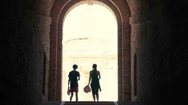 two of my firends walking up a tunnel to sunlight. This is in Ancona, Italy, which is amazingly beautiful btw. 
I really like the shilouettes of the both and the frame wich is that huge building.