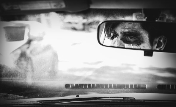 man in halloween costume staring at rear view mirror