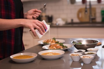 Woman pouring cooking cream in dal at home