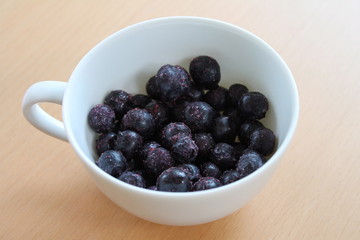 Frozen blueberries in a white cup.
