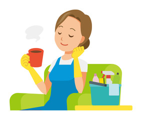 A woman wearing a blue apron and rubber gloves sits on the sofa and is drinking coffee