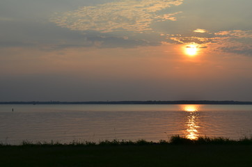 sunset through the clouds over a reservoir