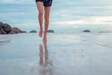 barefoot of young woman speed exercise on the sea beach in daily morning