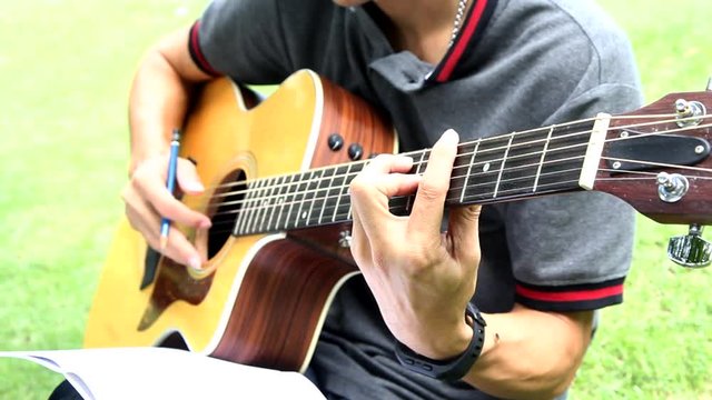 composer write note of song and use acoustic guitar for play