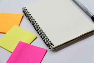 Blank page notebook with post-it note on office desk. 
