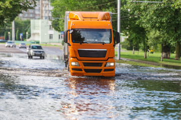 The large truck goes on the flooded city street after the strongest rain