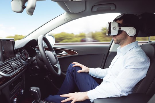 Businessman using virtual reality headset in a car 
