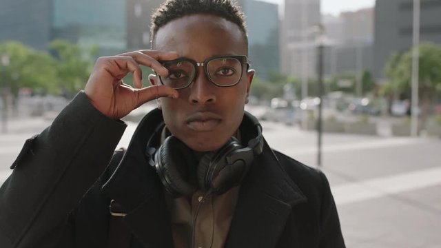 close up portrait of trendy african american man student intern puts on glasses smiling happy at camera enjoying college lifestyle