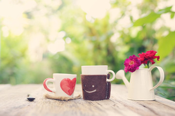 Heart pattern cup and smiling face cup with flower pot on wooden table