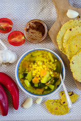 Vegetable corn soup with turmeric powder. Hot and spicy soup. Vegetarian lunch or vegan dinner with carrot and potato. Served with Indian traditional garlic naan flat bread or chapati (roti).