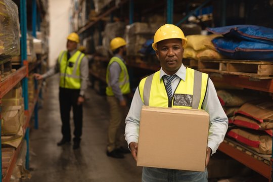 Male Staff holding cardboard box in warehouse