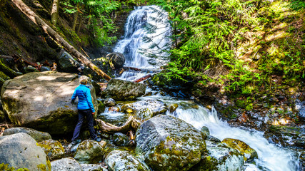 Senior Woman at Whitecroft Falls, a waterfall on McGillivray Creek and a short hike from Sun Peaks Road near the town of Whitecroft in the Shuswap region of the Okanagen in British Columbia, Canada