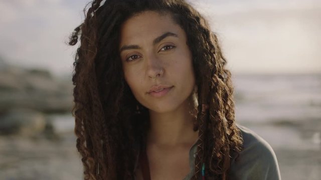 portrait of beautiful independent hispanic woman with dreadlocks looking pensive thoughtful at beach 