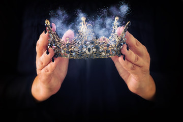 image of lady in black holding queen crown decorated with precious stones and magical glowing...