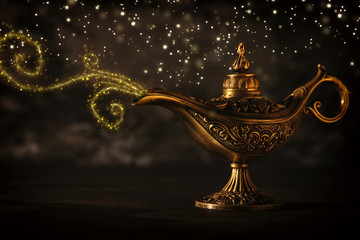 Image of magical mysterious aladdin lamp with glitter sparkle smoke over black background. Lamp of...