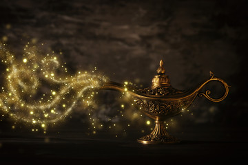 Image of magical mysterious aladdin lamp with glitter sparkle smoke over black background. Lamp of wishes. - obrazy, fototapety, plakaty