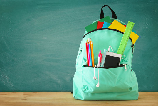 School Bag With Stationery And Notebooks In Front Of Blackboard. Back To School Concept.