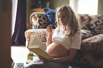 Pregnant woman reading a book in living room