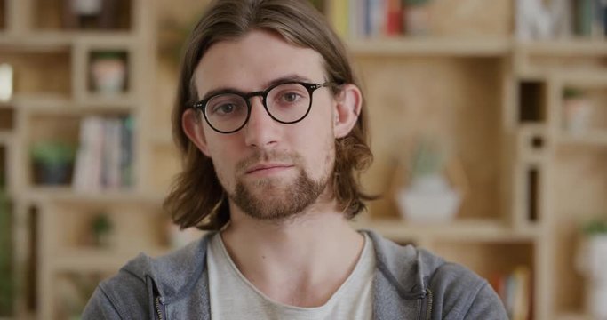close up portrait of cute young man geek looking serious at camera arms crossed handsome student nerd wearing glasses