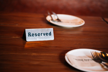 'Reserved' Sign on dining table in restaurant with spoon, fork and plate.