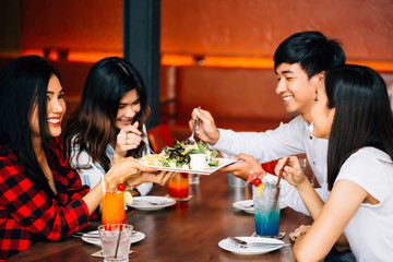 Group of Asian happy and smiling young man and women having a meal together with enjoyment and happiness.