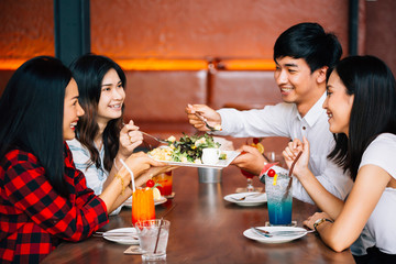 Group of Asian happy and smiling young man and women having a meal together with enjoyment and happiness.