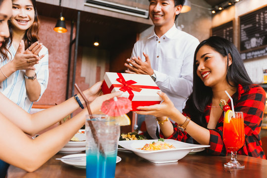 Group of Asian people clapping hands to congratulate each other for birthday gift or rewards during dinner.