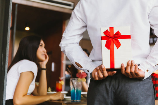 Asian woman expected to receive a surprise present gift box from man as a romantic couple for occasional anniversary celebration.
