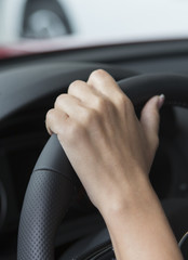 The hand of a girl with a stylish manicure lies on the handlebars in a saloon car.