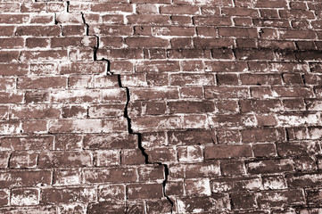 Part of the red brick wall of an old house with figured cracks due to the destruction of the Foundation. Toned
