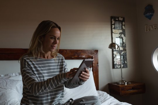 Woman using digital tablet in bedroom