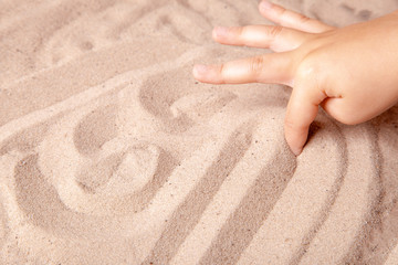 Naklejka na ściany i meble Child draws a finger on the sand