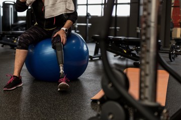 Worried woman sitting on exercise ball in the gym