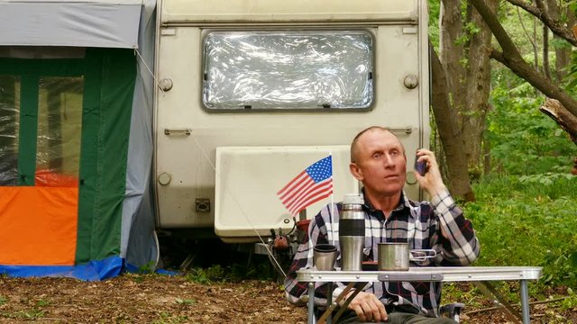 4K. American Man traveler  talk mobile phone in wood