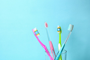 Cup with toothbrushes against color background. Dental care